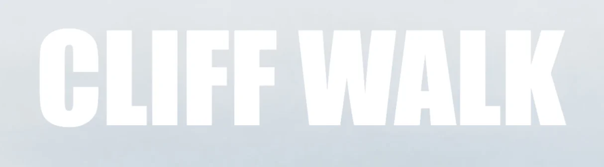 Le lettere bianche CLIFF WALK su un cielo grigio chiaro, difficili da leggere