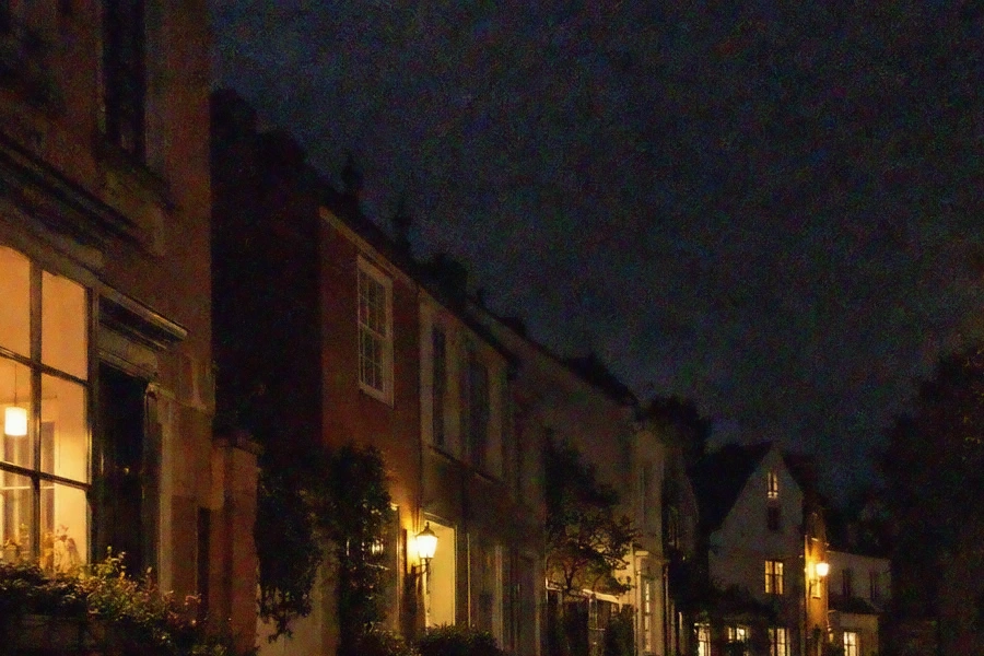 Facciate di case e cielo notturno con finestre illuminate: prima sgranati e pieni di puntini colorati, dopo la riduzione del disturbo con molta meno grana e meno puntini
